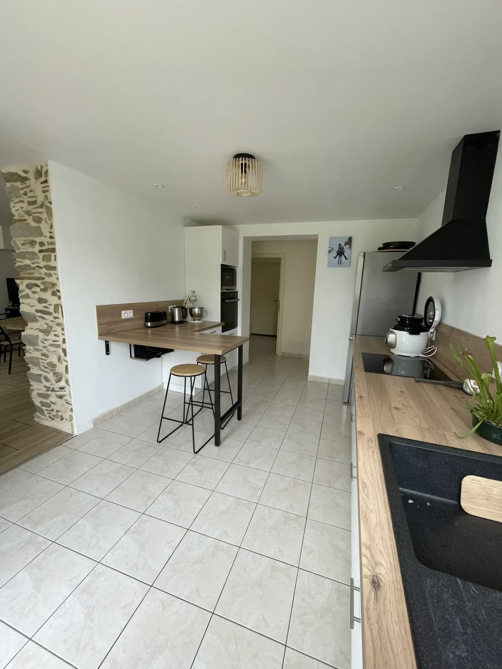 Rénovation d'une cuisine noire et bois avec mur en pierre